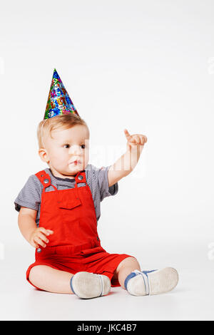baby boy with birthday hat in overall red shorts Stock Photo