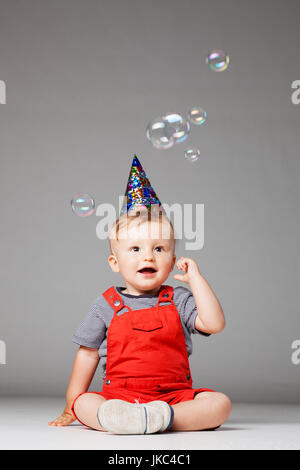 happy baby boy with birthday hat and foam balloons, studio shot Stock Photo