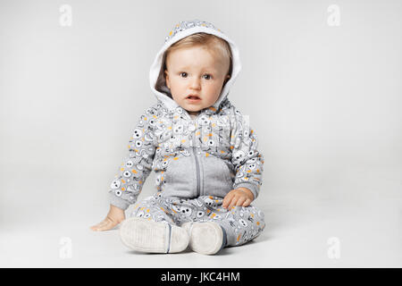 baby boy sitting on the ground, looking at camera, serious expression Stock Photo