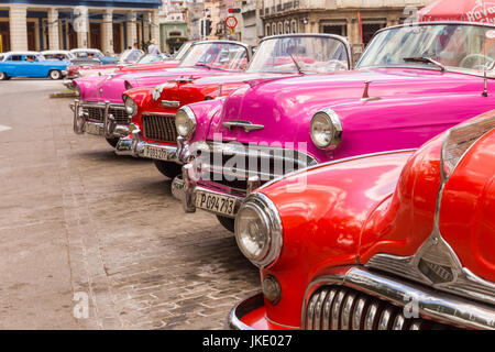 Row of classic vintage American cars in retro red, orange and pink in Old Havana, Cuba Stock Photo