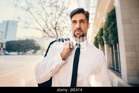 Portrait of handsome young man in formal wear walking outside on the city street. Caucasian businessman walking down the street. Stock Photo