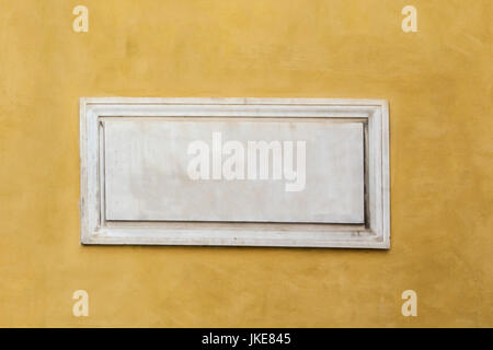 White marble classic blank nameplate with empty space for text and numbers centered on yellow painted wall of old Italian house in Rome. Vintage backg Stock Photo