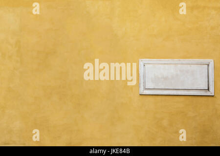 White marble classic blank nameplate with empty space for text and numbers on yellow painted wall of old Italian house in Rome. Vintage background wit Stock Photo