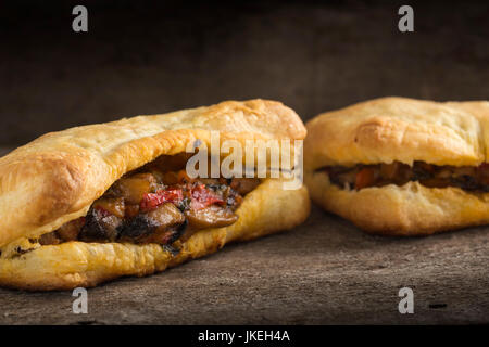 Puff pastry stuffed with mushrooms and vegetables on wooden background Stock Photo