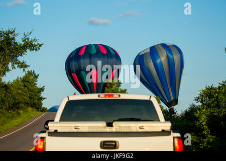 Three hot air ballons holding up traffic as they land next to a Wisconin road in July Stock Photo