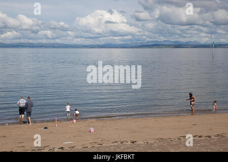 Morecambe, Lancashire. UK Weather. 23rd July, 2017. Warm sunny day at the coast as the high tide reflecs the distant hills of the Lake District.  This popular coast town can offer spectacular views of the Cumbrian hillsides when conditons are right. Credit: MediaWorldImages/Alamy Live News Stock Photo