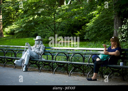 New York City, Manhattan, Central Park silver diamante covered suit busker waiting on benches posing for tips Stock Photo