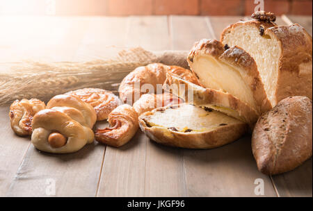 Assortment of baked bread and wheat on wood table background, homemade bakery Stock Photo