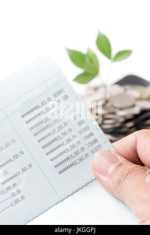 hand holding bankbook or passbook and plant growing out of silver coins on gardening trowel background selective focus on number, saving, investment a Stock Photo