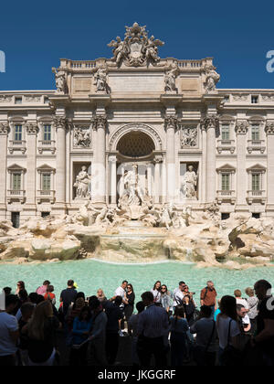 Vertical view of tourists taking photos around the Trevi Fountain in Rome.
