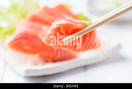 closed up of salmon sashimi set with chopsticks holding a piece of sliced salmon, healthy food and diet Stock Photo