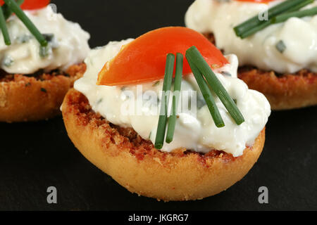 toasted buschetta slices with cottage cheese tomato and chives Stock Photo