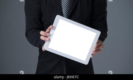 Businessman holding tablet in black suit on gray background Stock Photo