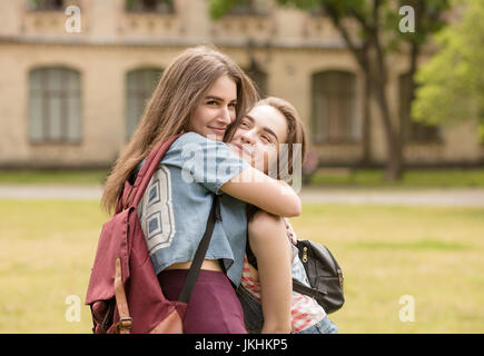 Two female student hug in university campus. Stock Photo