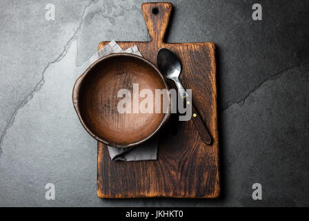 Cooking background. Vintage empty clay bowl on cutting boards, copy space. Stock Photo