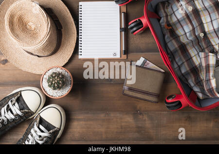 Travel preparations on wooden table, hat wallet, bag, notebook and shirt Stock Photo