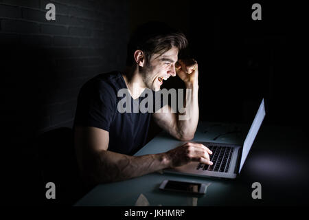 Young man working on computer at night in dark office the designer works in the later time. Hacker Stock Photo