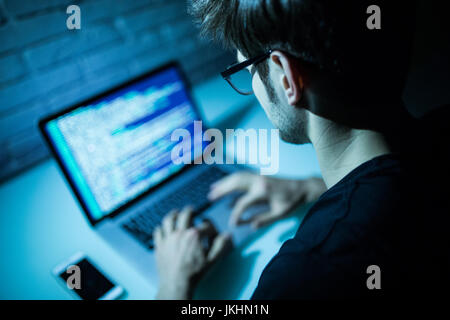 Man using laptop writing programming code on laptop Stock Photo