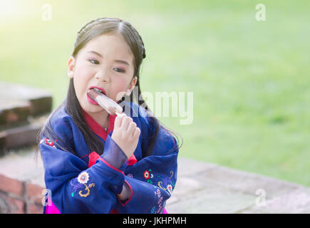 cute girl wearing Japaness costumes eating ice-cream in park. Stock Photo