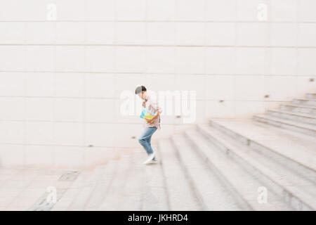 Male student going down the stairs, blurred motion Stock Photo
