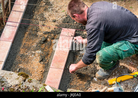 Nahaufnahme, Bauarbeiter bei der Herstellung einer Maurer aus Ziegelsteinen auf der Baustelle. Stock Photo