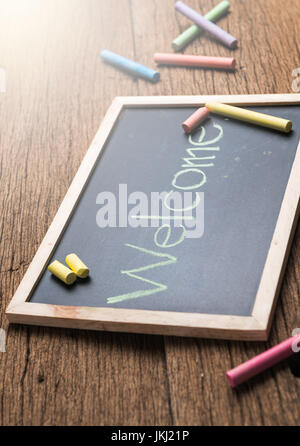 welcome- green chalk text on a vintage slate blackboard on old wood background Stock Photo
