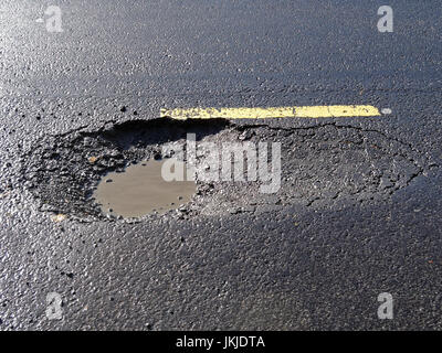 large pothole on road filled with water glasgow scotland uk Stock Photo