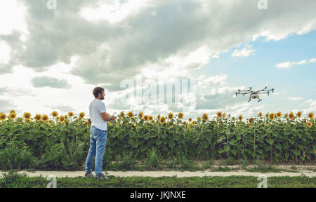 Young man watching and navigating a flying drone in blue clear sky Stock Photo