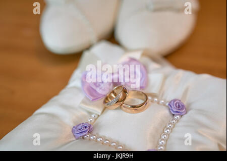 White bride shoes and wedding rings on wooden floor Stock Photo