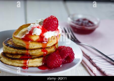 Pile of pancakes with fresh raspberries and a little whipped cream dripping red berry sauce Stock Photo
