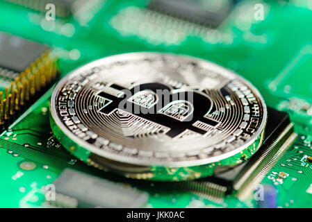 Silver Bitcoin virtual currency on a circuit board background Stock Photo