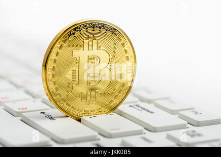 Golden Bitcoin on white keyboard over white background Stock Photo