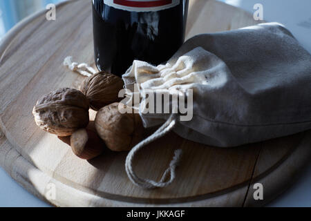 Pile of walnuts in shellin a bag on a wooden background . Linen sack with walnuts in the background. Stock Photo