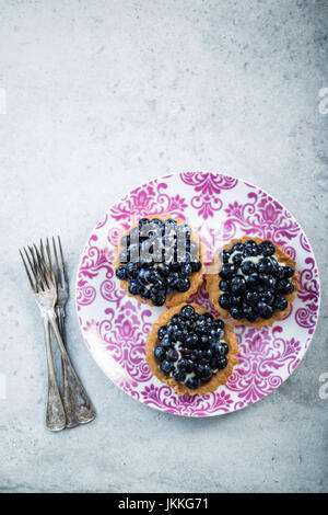 Fresh blueberry tart on vibrant plate, overhead Stock Photo