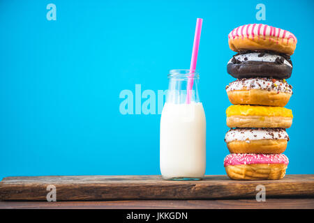 Milk bottle and stack of donuts on wooden board, negative space bright background Stock Photo