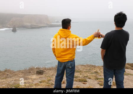 Two young Asian men raise a toast to the beautiful view, Davenport CA. Stock Photo