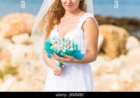 Close-up of wedding bouquet with seashells in hands of the bride. Stock Photo