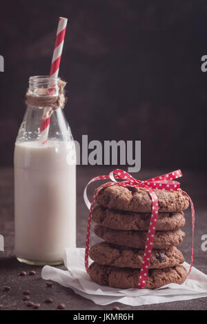 freshly baked chocolate chip cookies with milk on rustic background Stock Photo