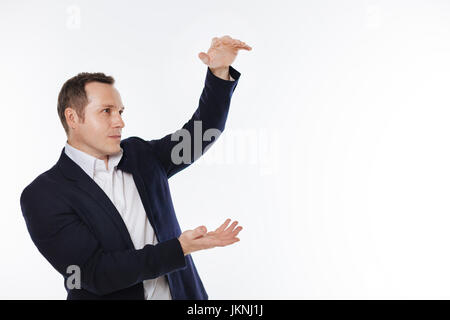 Neat engaged gentleman holding some object in his hands Stock Photo