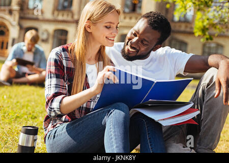 Charismatic positive guy helping his friend with the subject Stock Photo