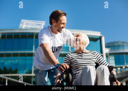 Handsome charismatic man entertaining elderly lady Stock Photo