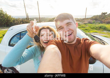 Auto business, car sale, deal and people concept - Happy funny beautiful couple shows key with new car on background Stock Photo