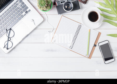 blank notebook with computer, smart phone, coffee and vintage camera on white wood background, business concept Stock Photo