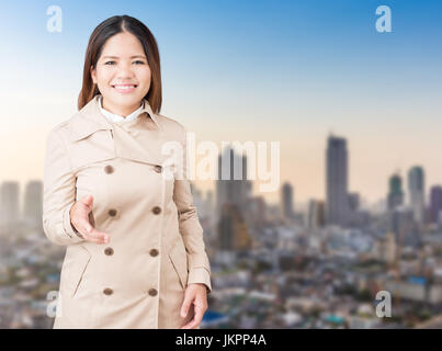 asian woman wearing brown coat extending hand to shake Stock Photo