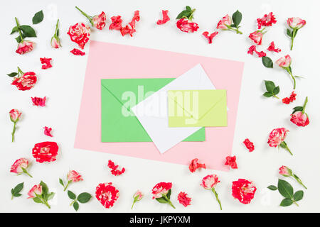 Flowers composition. Frame made of rose flowers and colorful envelopes in the middle. Flat lay, top view Stock Photo