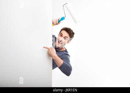 handsome man holding paint roller and pointing on blank card isolated on white, handyman tools concept Stock Photo