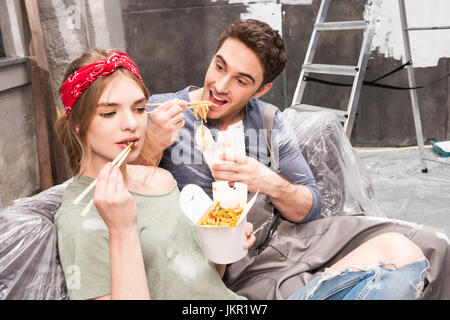 couple eating thai food while resting during renovation home process Stock Photo