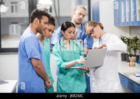 group of medical workers using laptop during discussion in lab Stock Photo