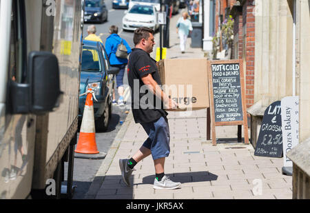 Man making a delivery, carrying a heavy box from a van. Stock Photo