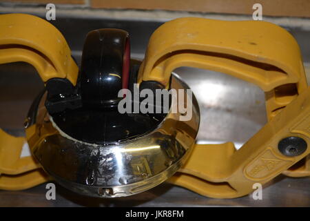 Close up of electric kettle lid in shiny stainless steel and black plastic being held in two clamps vices on steel sink surface whilst being repaired Stock Photo